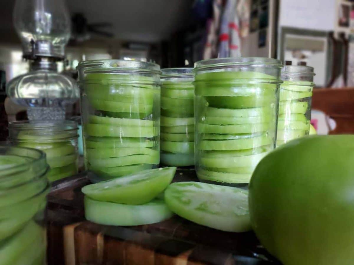 Canning sliced green tomatoes for frying in glass jars.