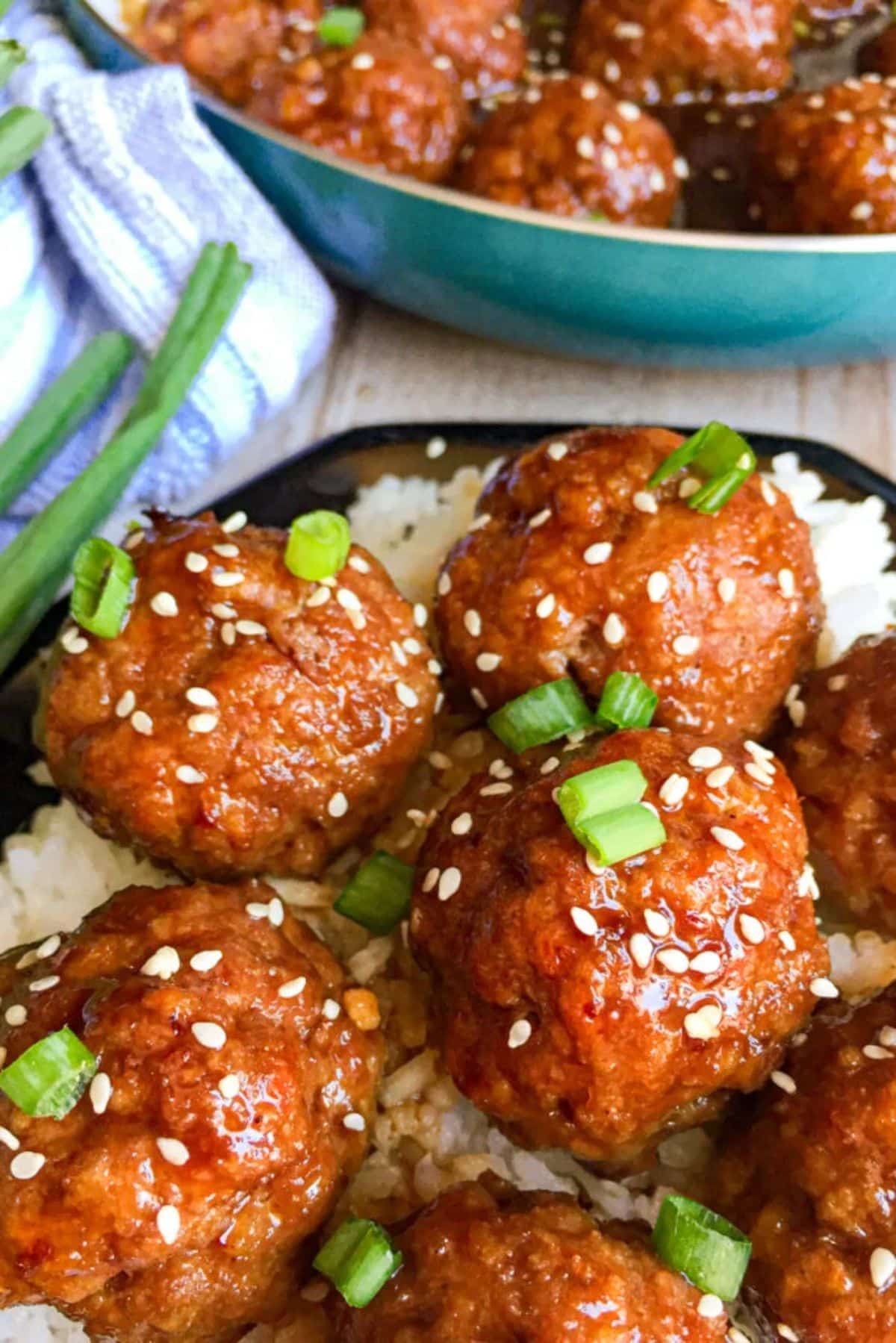 Sweet and spicy asian turkey meatballs with rice on a black plate.