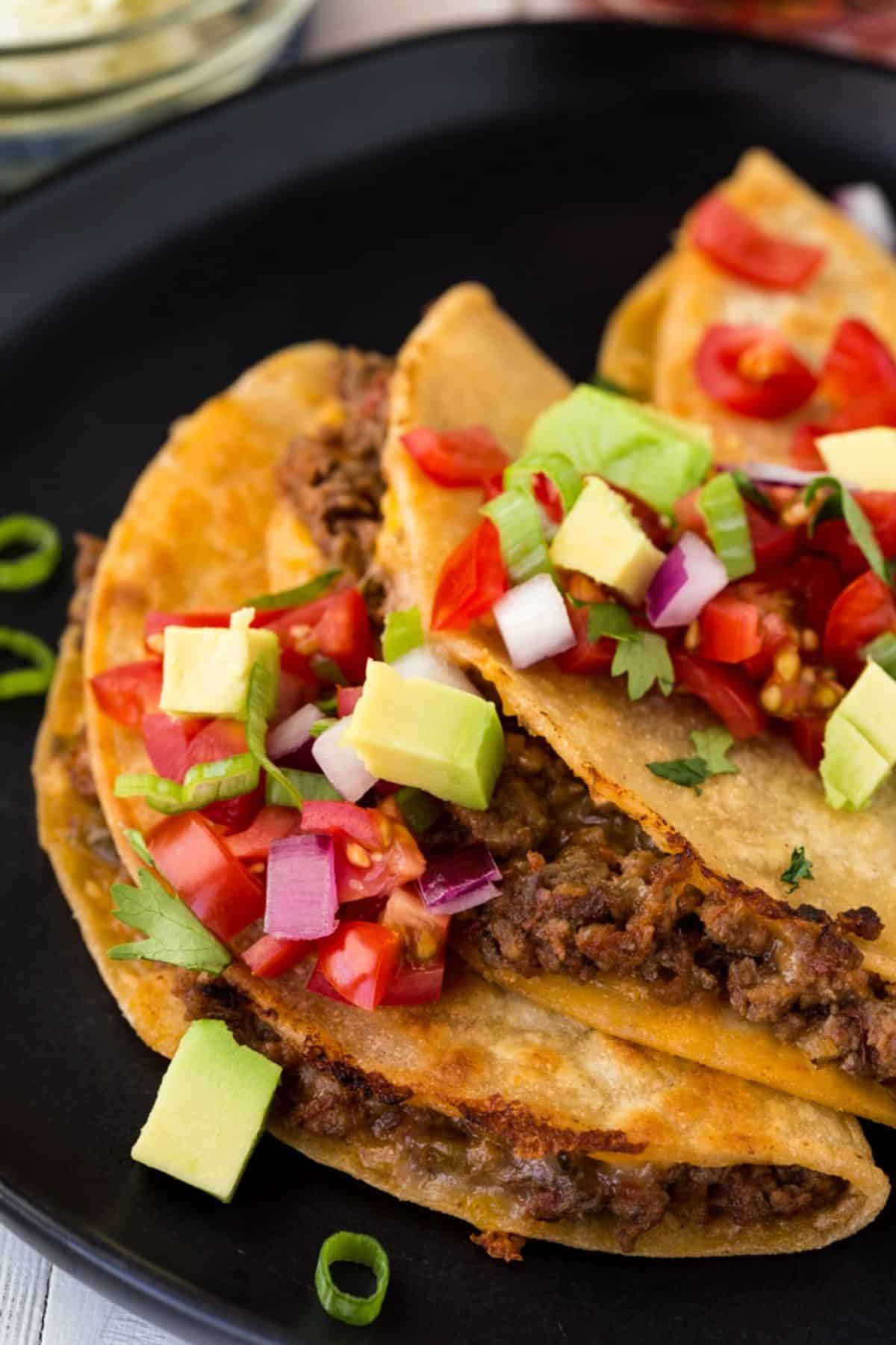 Griddle beef tacos on a black plate.