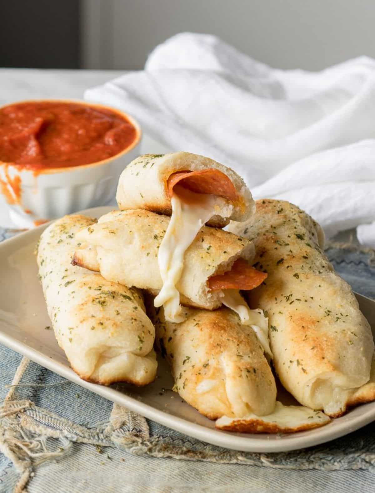 Crunchy cheesy pepperoni pizza sticks on a gray tray.