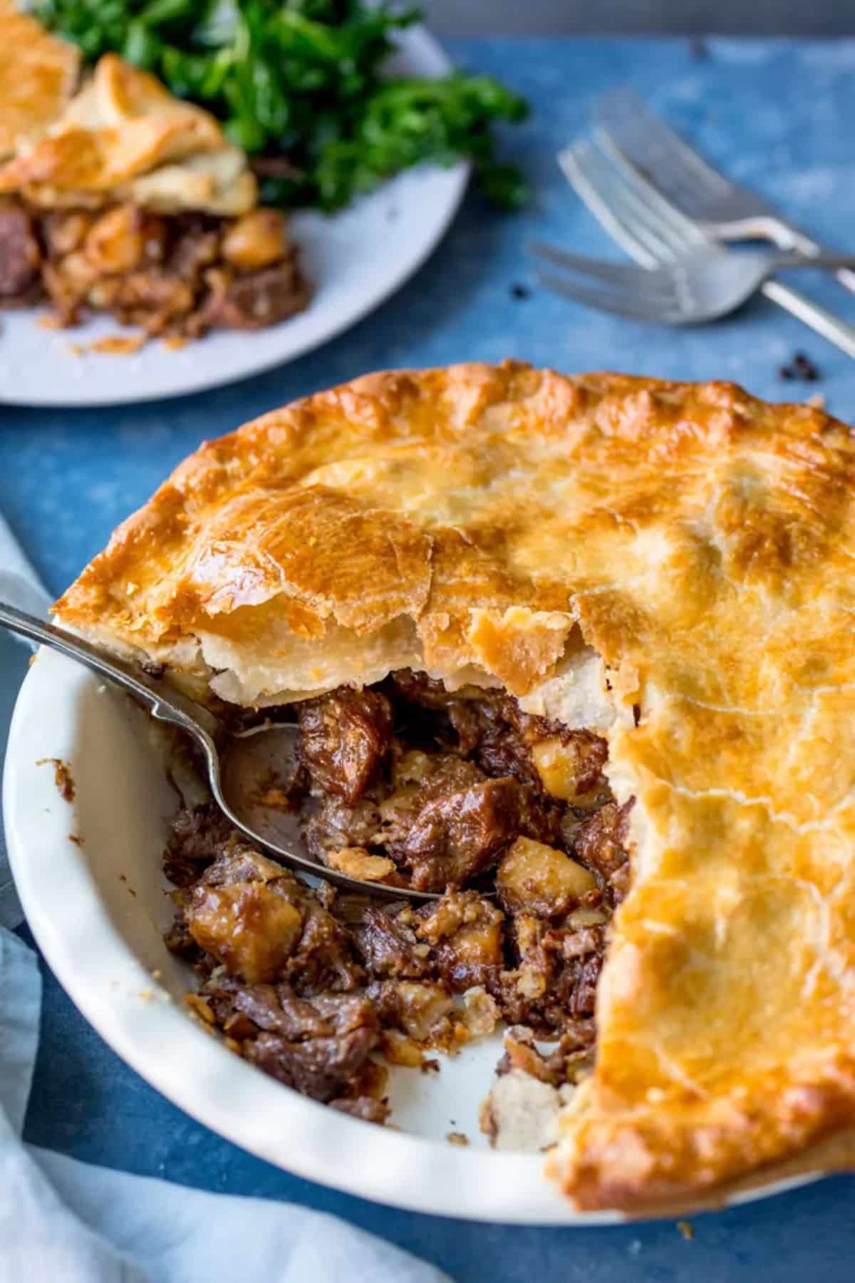 Juicy steak pie in a white bowl with a spoon.