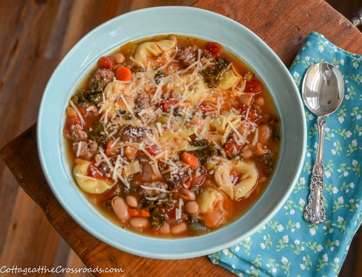 Italian sausage and cheese tortellini soup in a blue bowl.