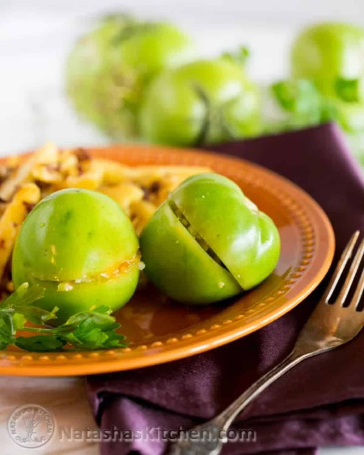 Pickled stuffed green tomatoes on a brown plate.