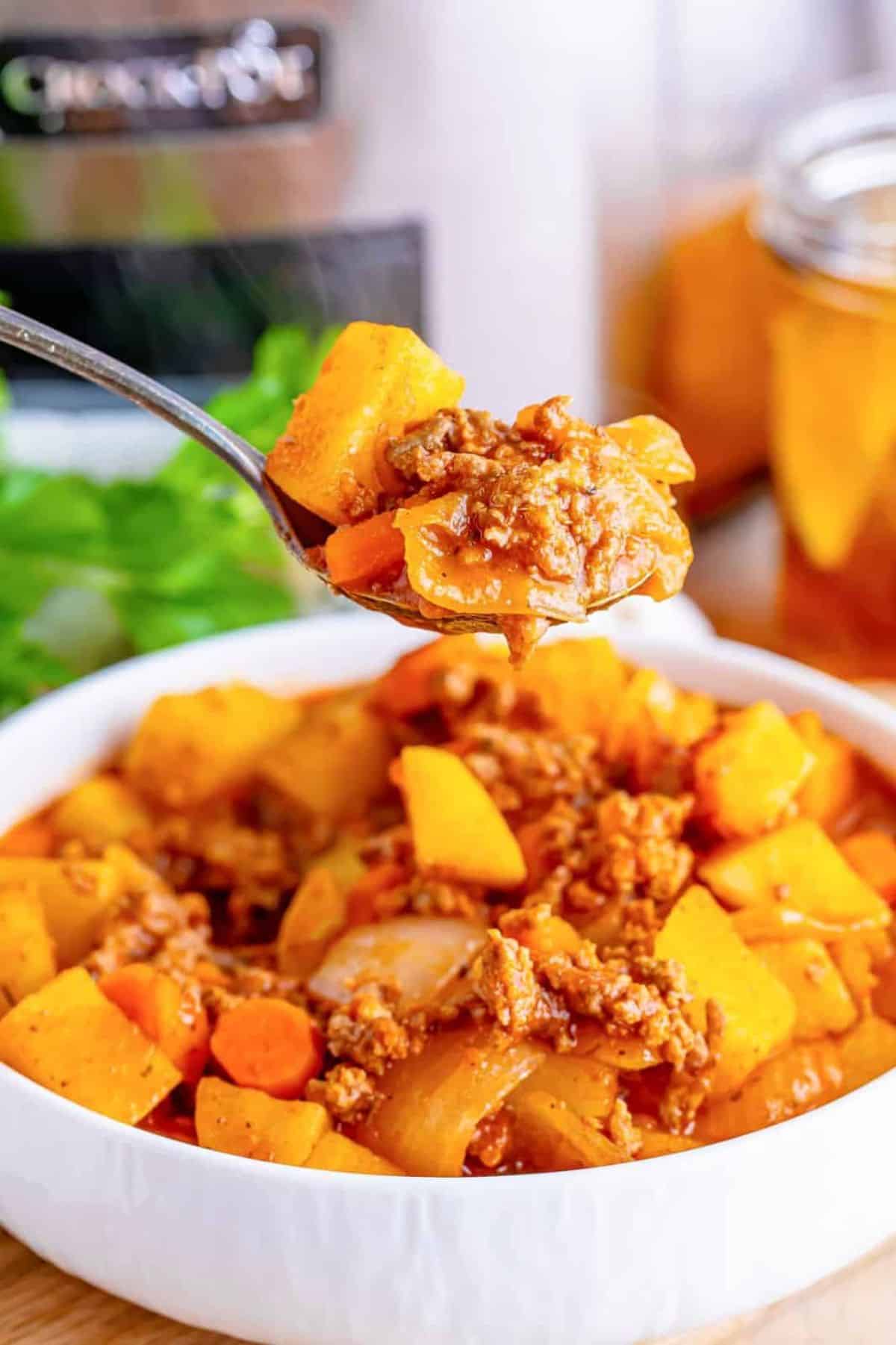 Crockpot stew in a white bowl and on a spoon.