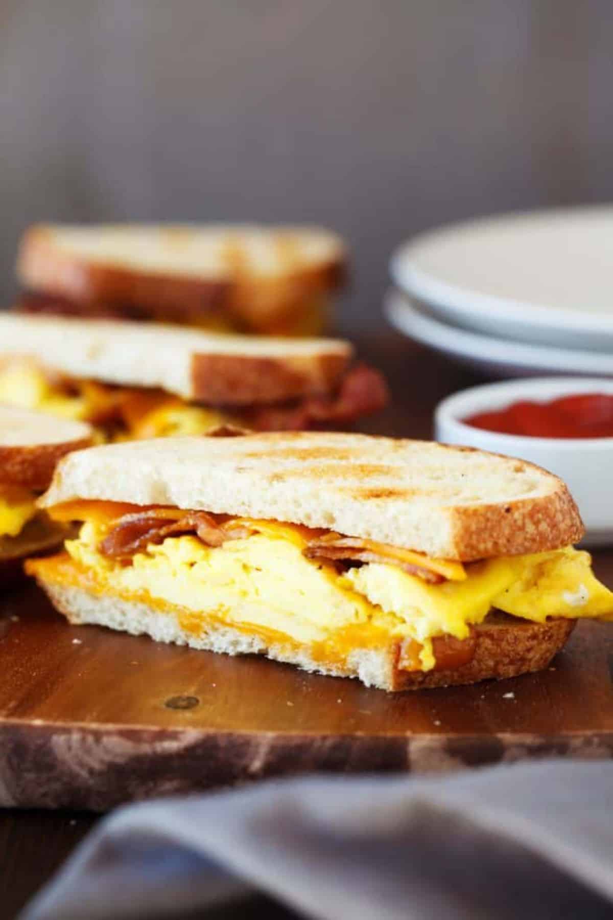 Griddle breakfast sandwich on a wooden cutting board.