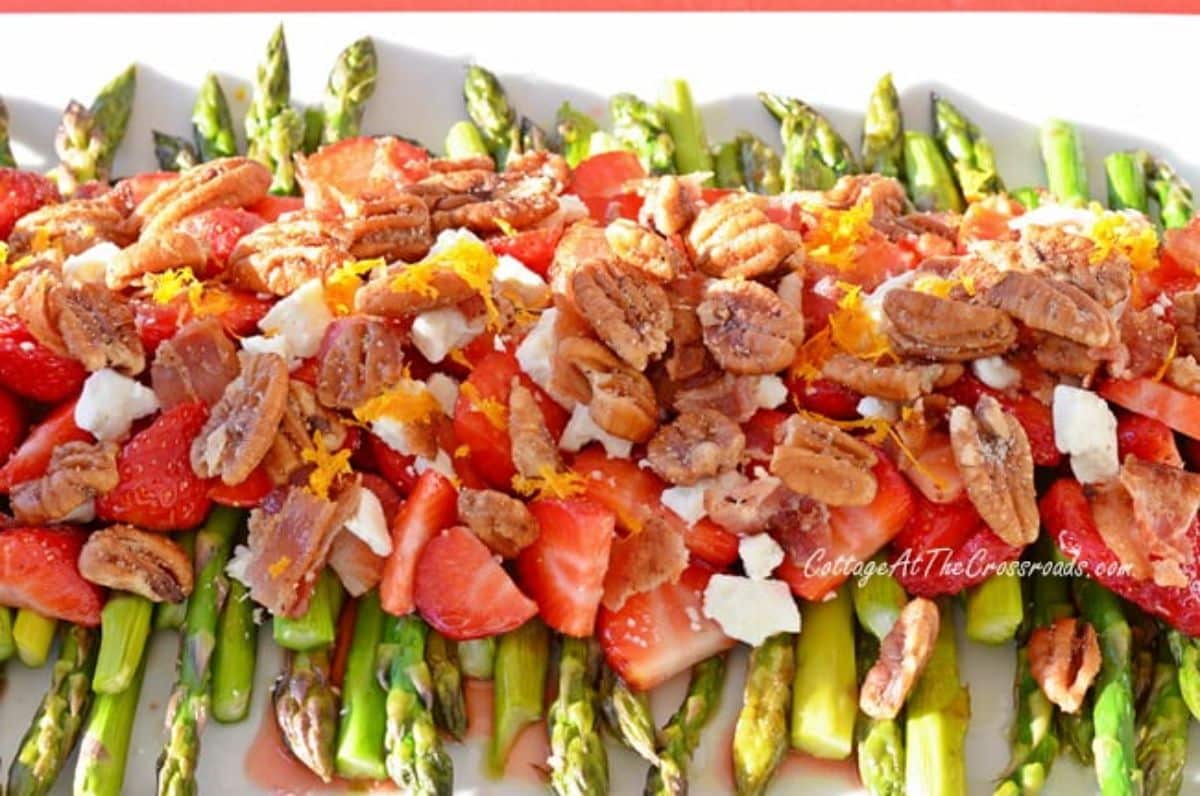 Asparagus strawberry salad with orange balsamic dressing on a white tray.