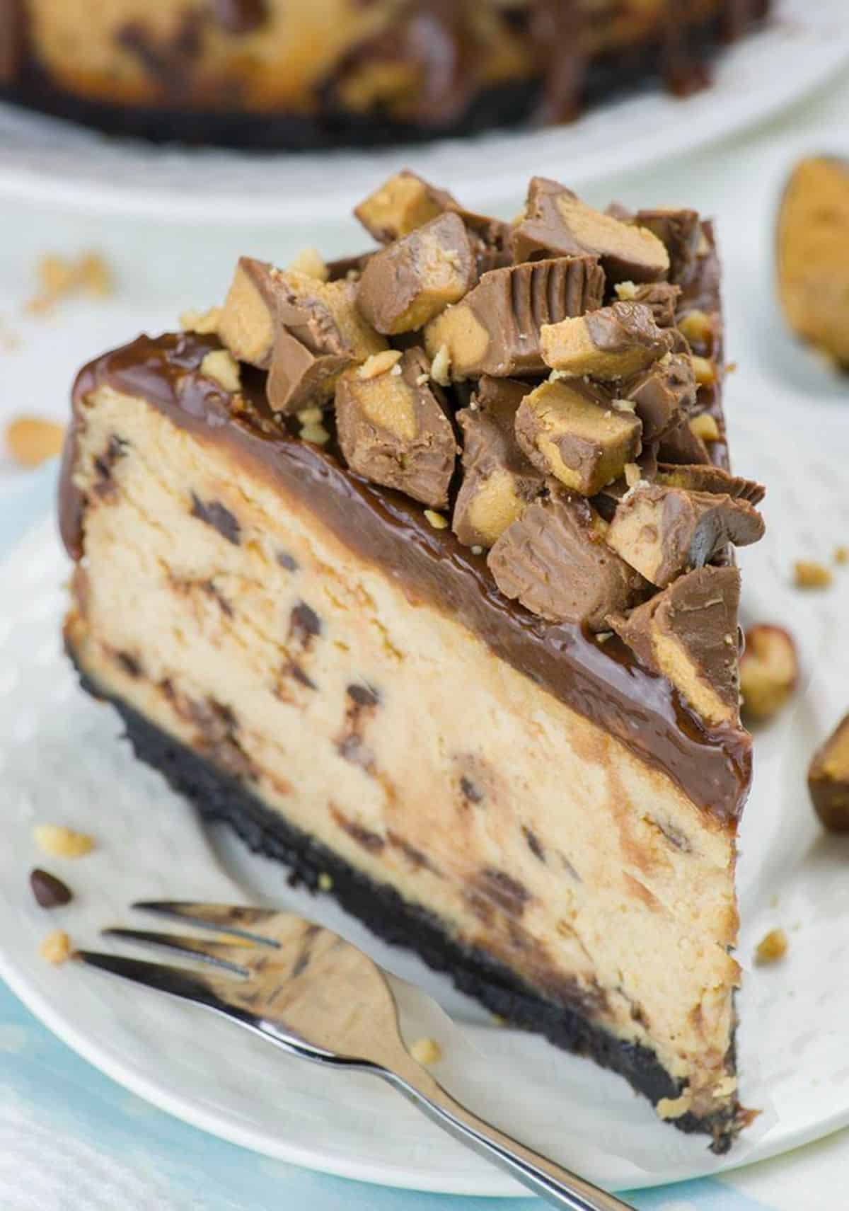 A piece of chocolate peanut butter cheesecake on a white plate with a fork.