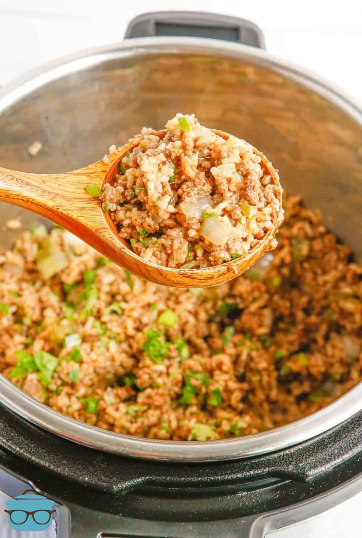 Beef dirty rice in a pot and on a wooden spoon.