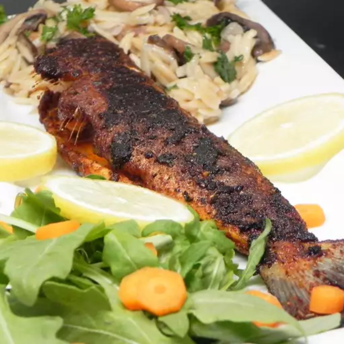 Blackened fish with rice and veggies on a white tray.