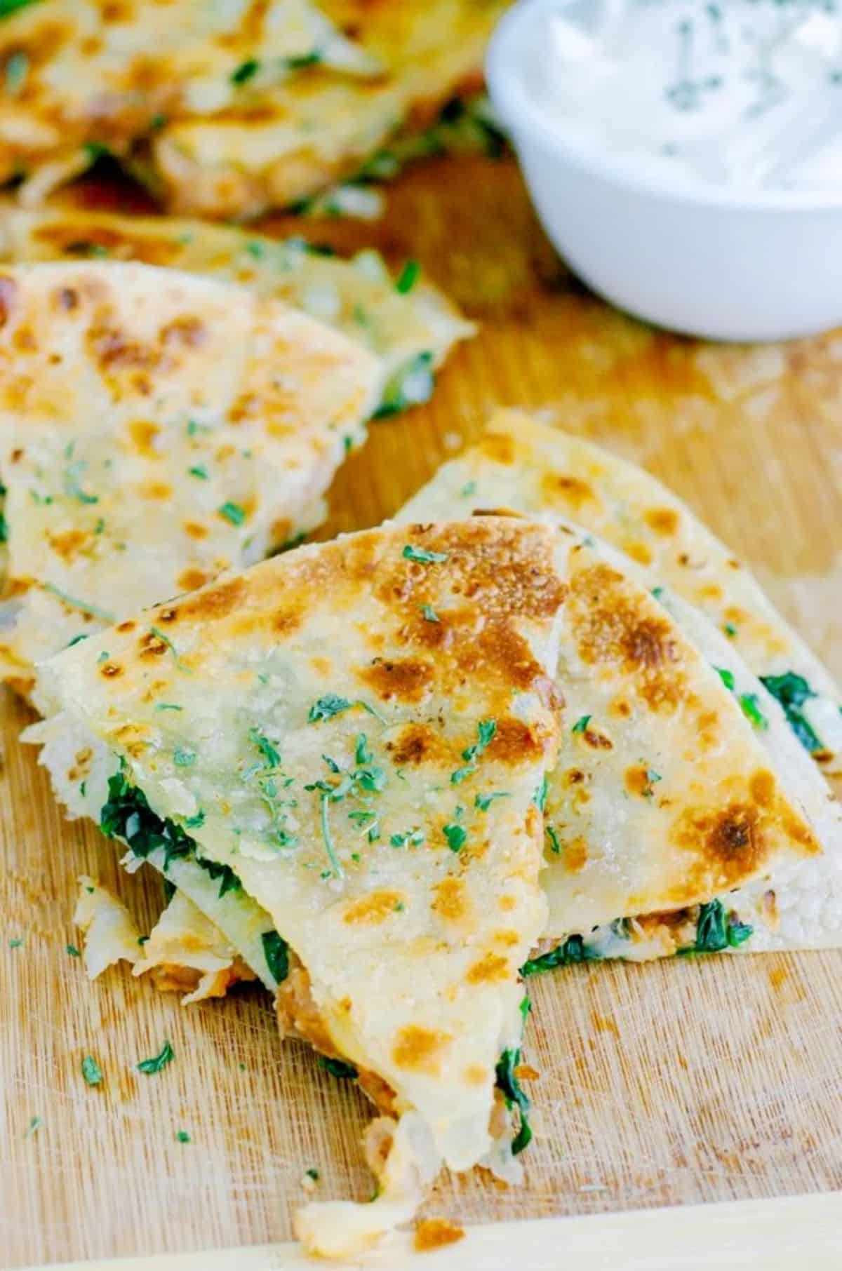 Crunchy spinach quesadillas on a wooden tray.