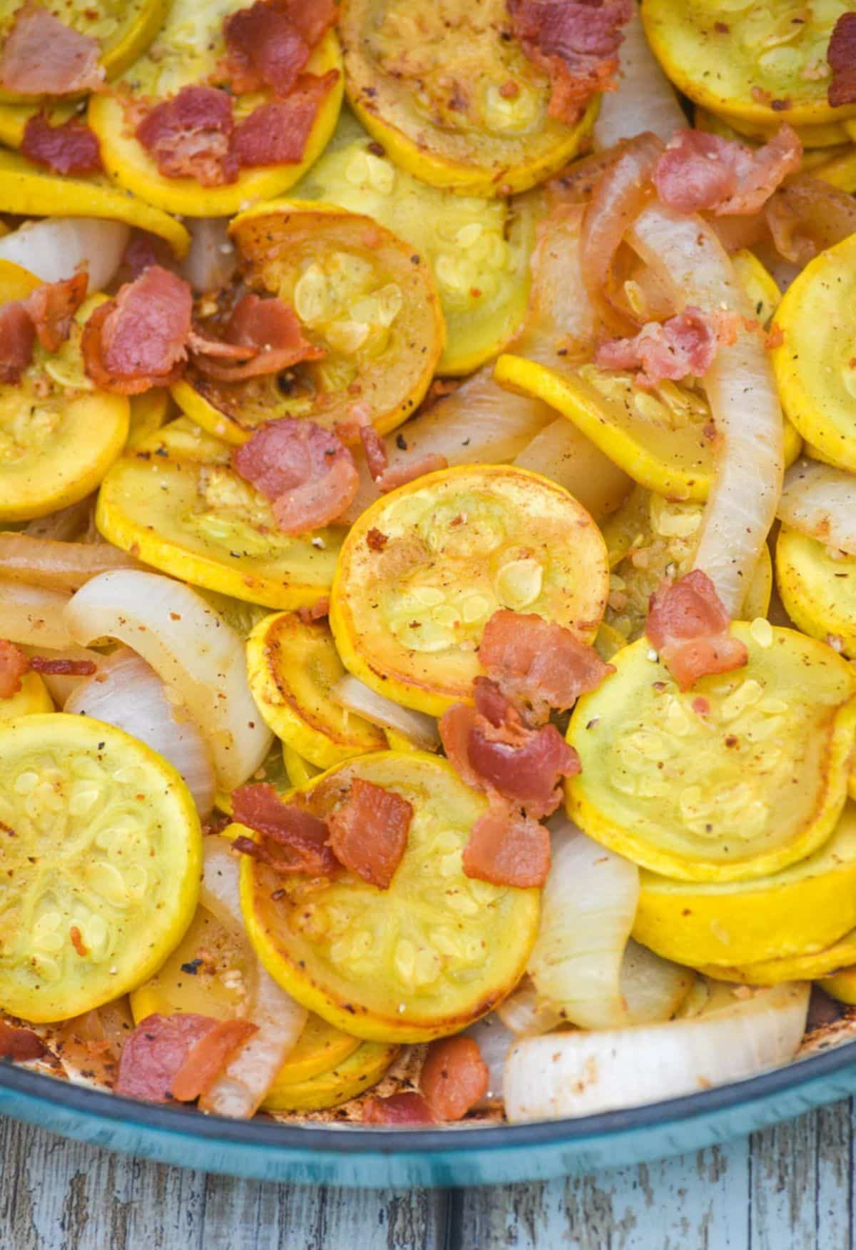 Sauteed summer squash with bacon and onions in a bowl.