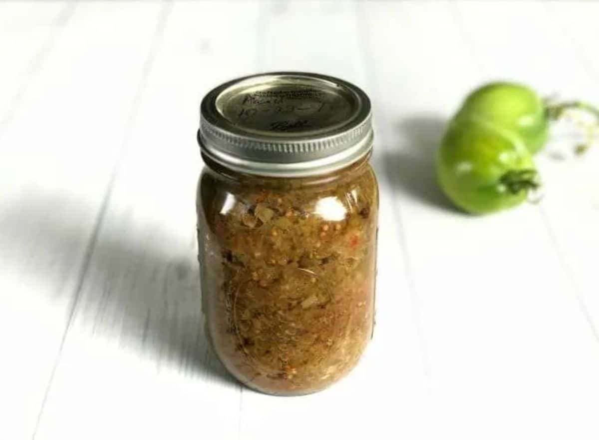 Piccalilli canning green tomato relish in a glass jar.