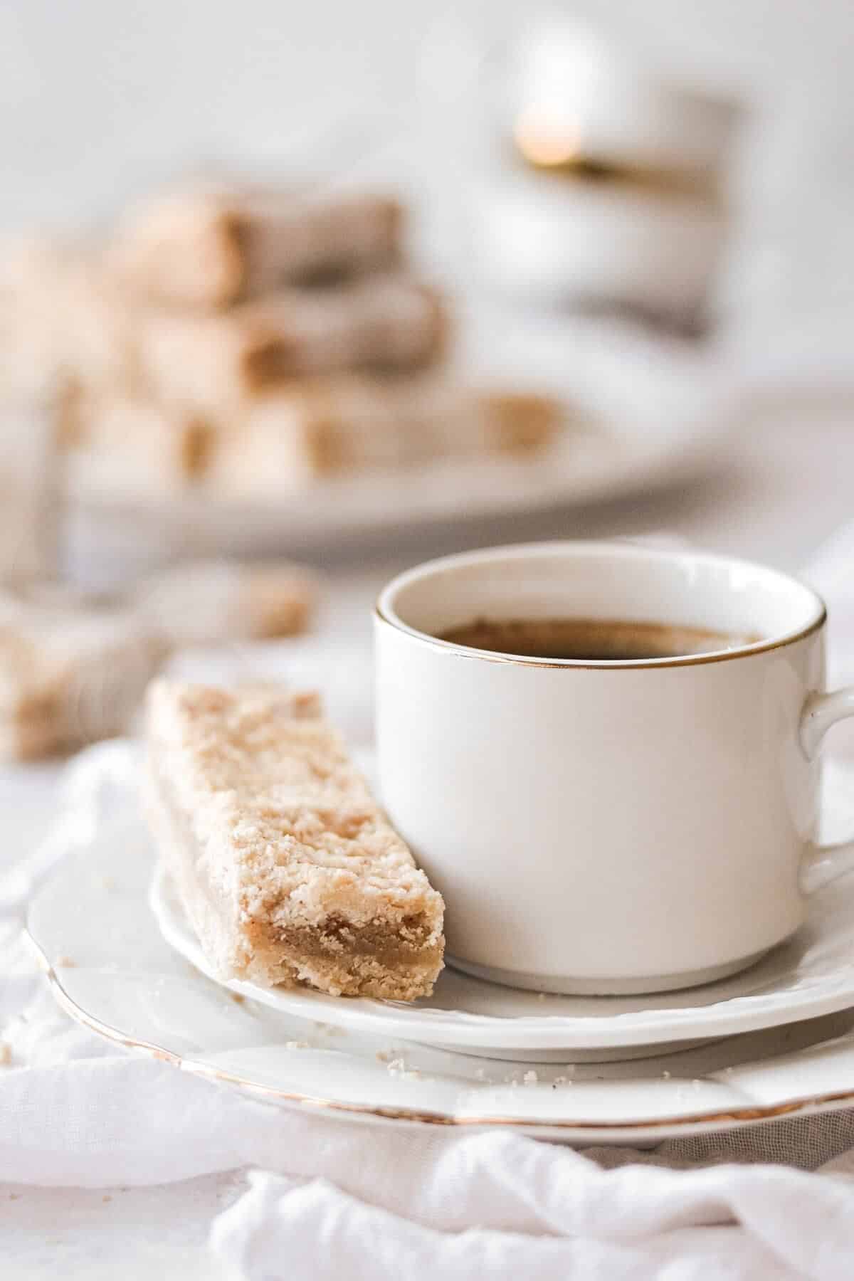 Almond crumble bar with a cup of coffee on a white plate.