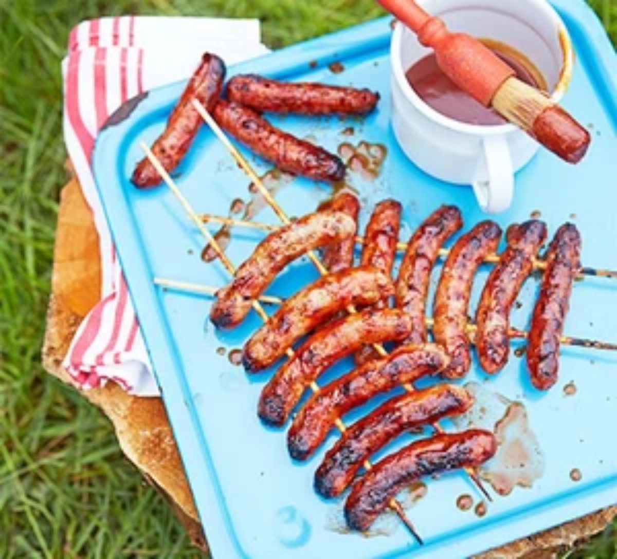 Bbq sausages with smoky tomato sauce on a blue tray.