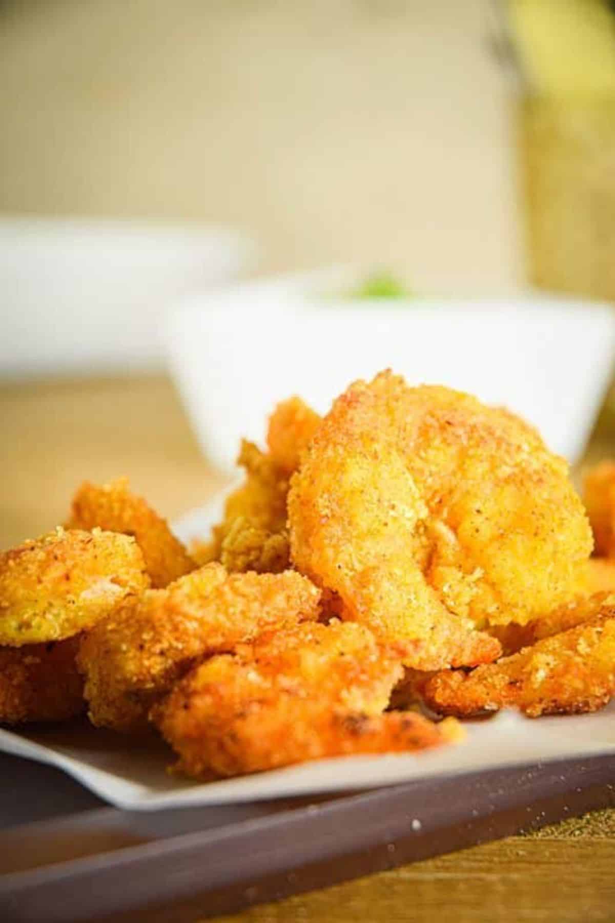 Electric skillet coconut shrimp with curry mayo on a paper napkin.