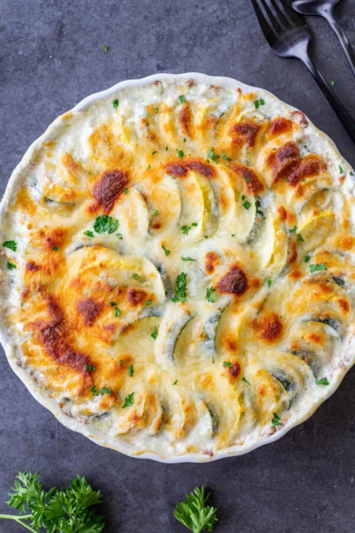 Cheesy zucchini and squash in a white casserole.