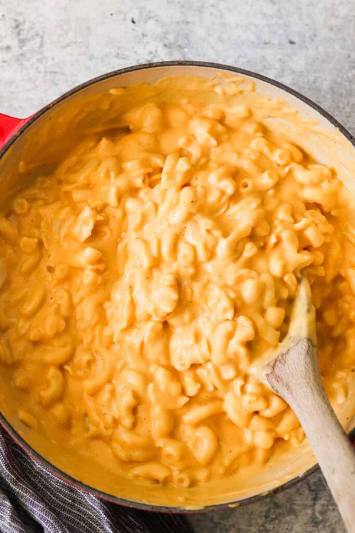 Hidden veggie mac n cheese in a bowl with a wooden spatula.