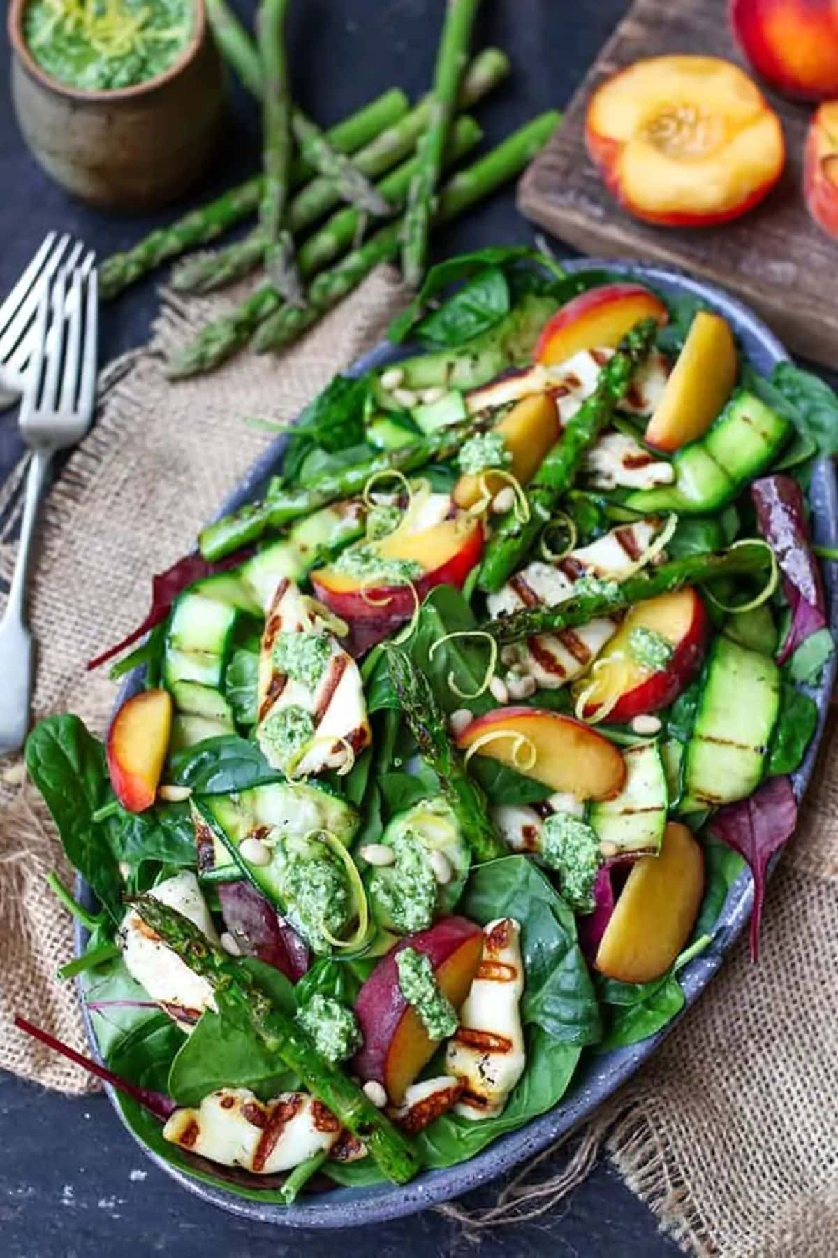 Griddled halloumi and peach salad with homemade lemon pesto on a blue tray.