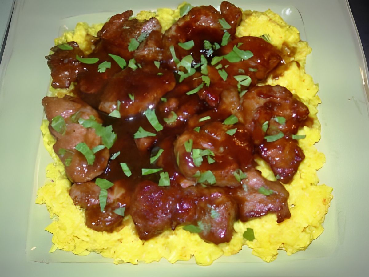 Pork medallions with yellow rice on a gray plate.