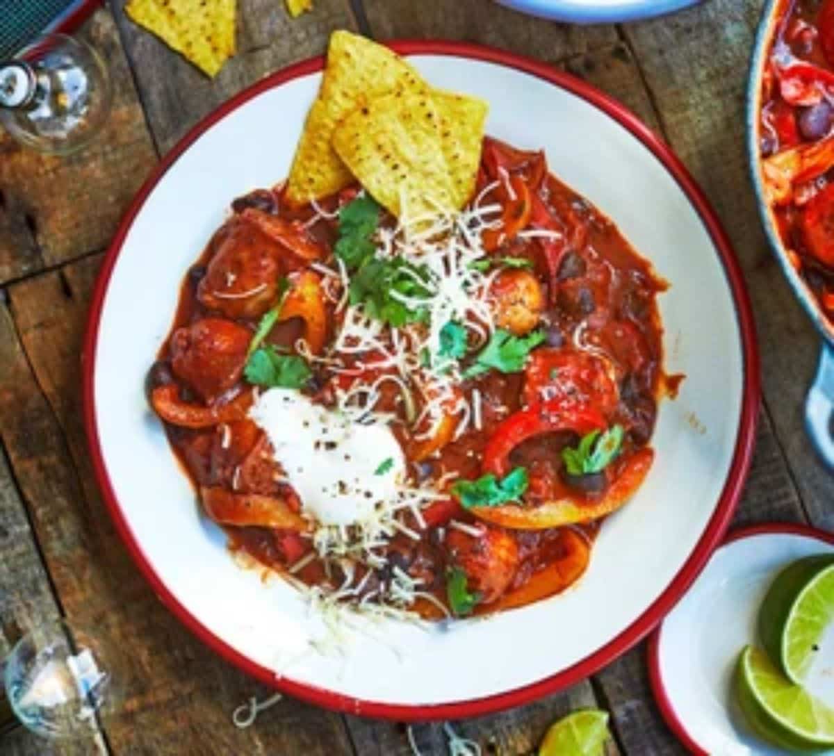 Smoky sausage & black bean chili on a white-red plate.