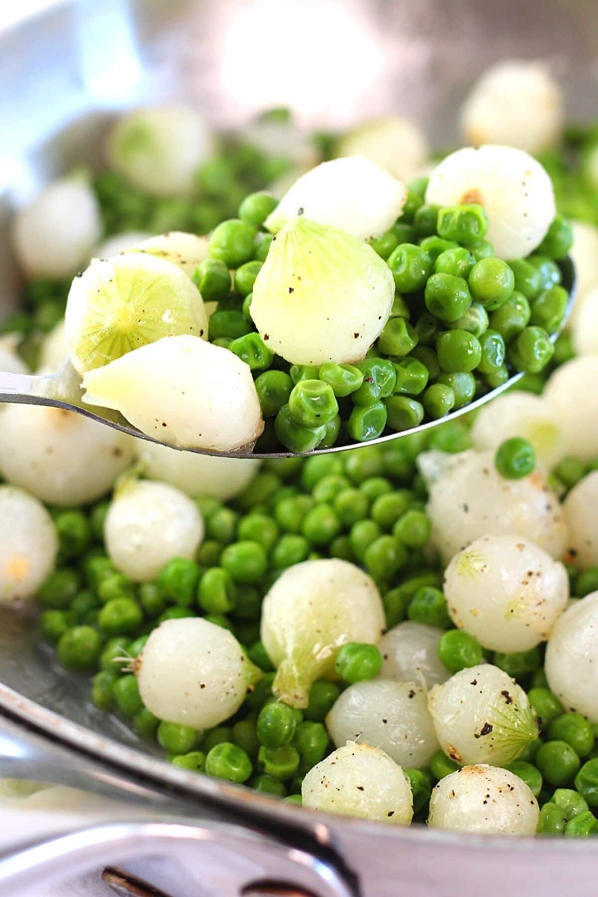 Sauteed peas and pearl onions in a bowl and on a spoon.