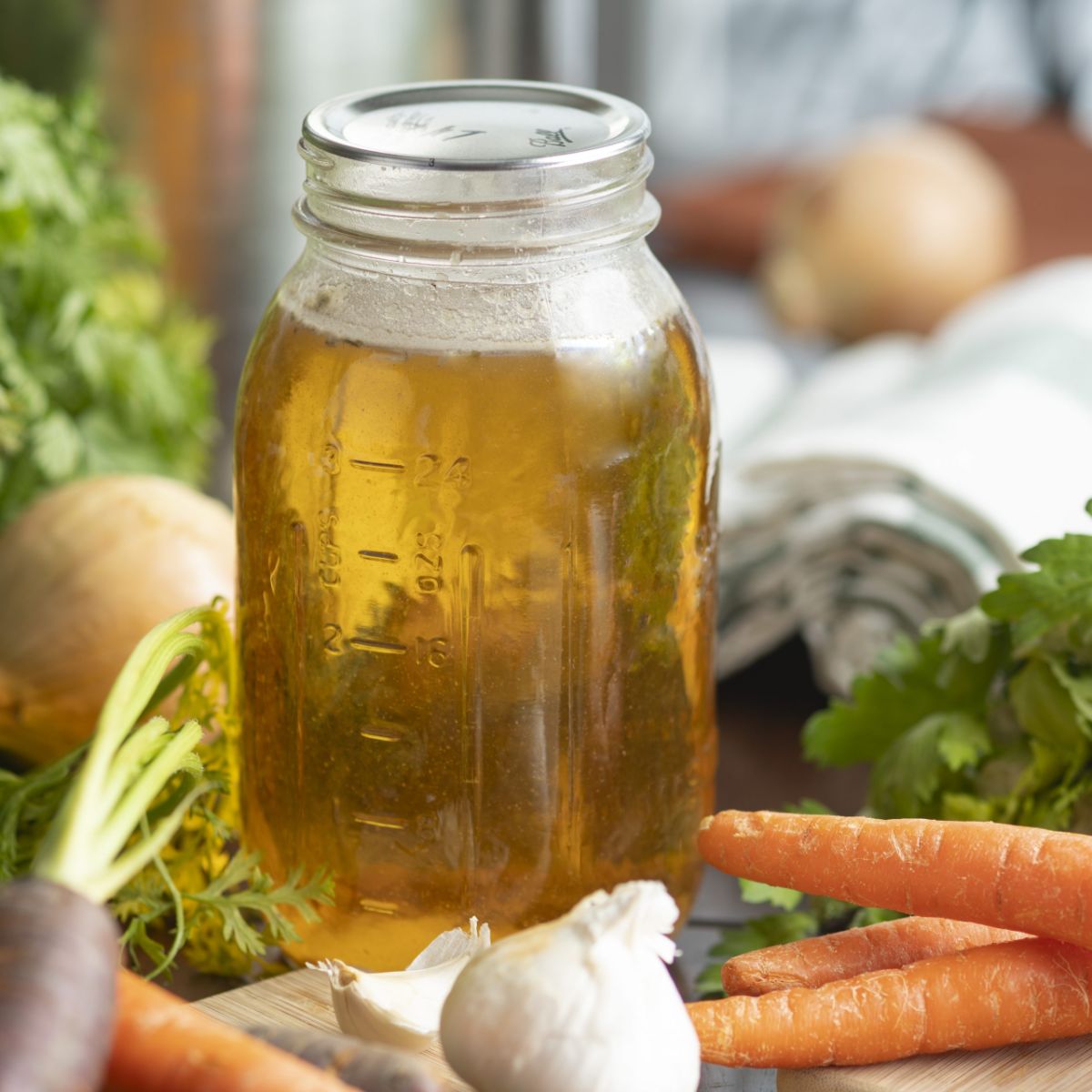 Canned asparagus soup in a glass jar with veggies around.