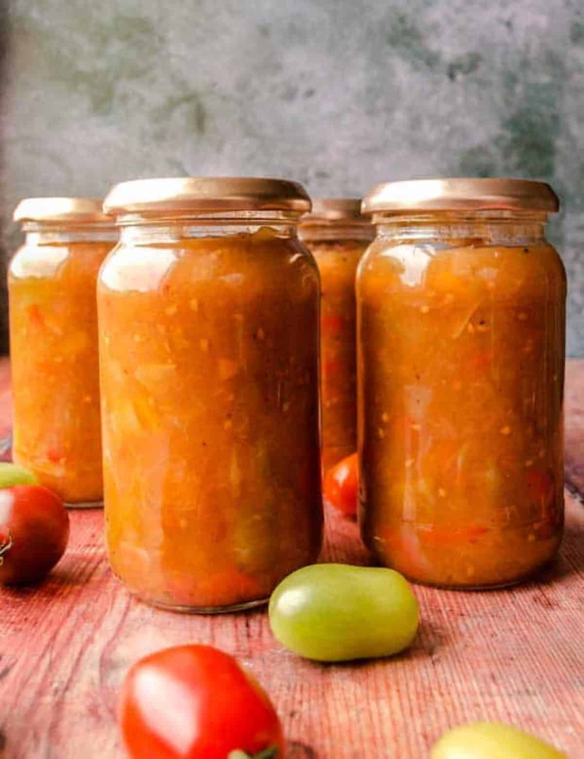 Green tomato and pepper chutney canned in glass jars.