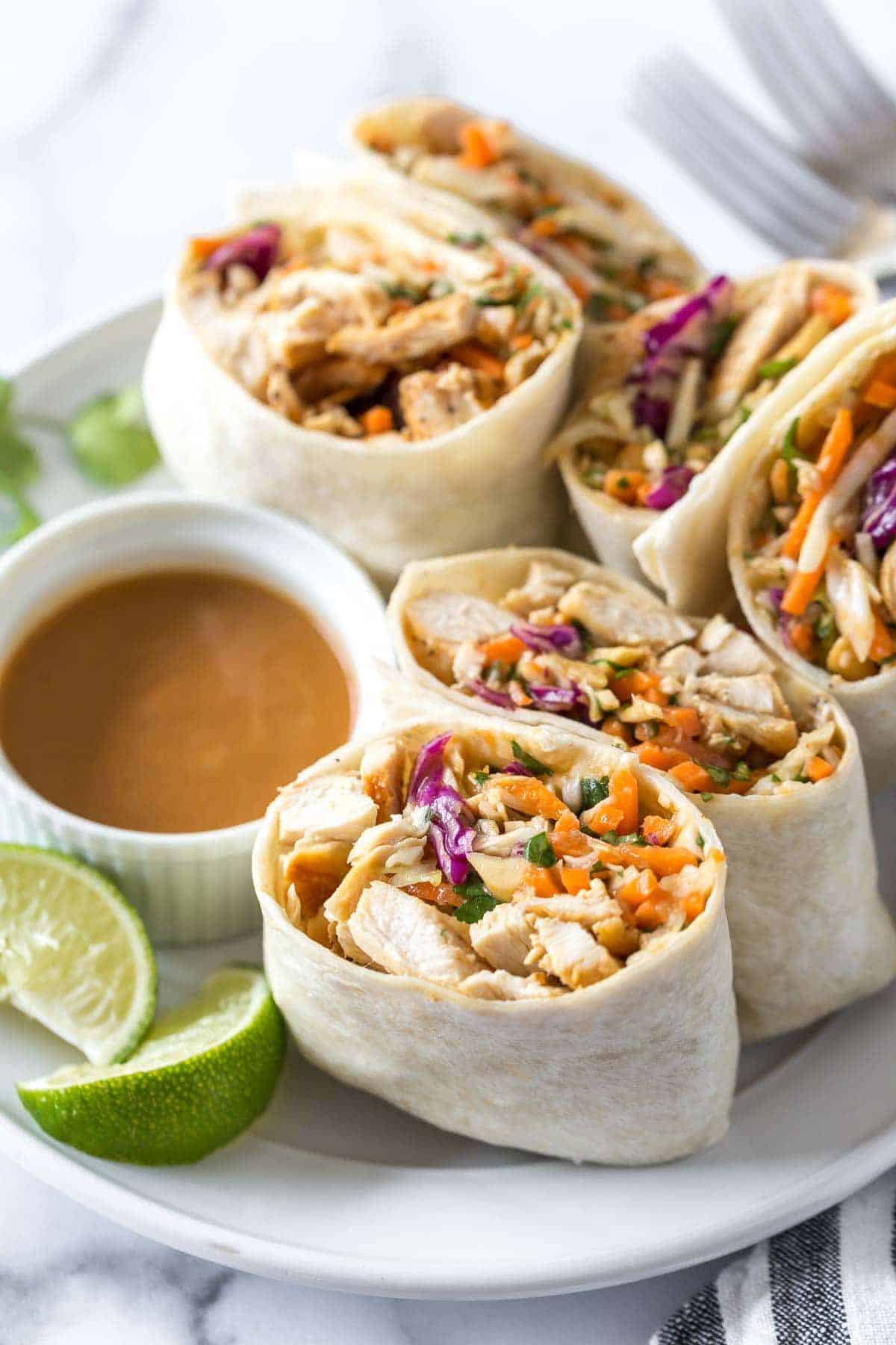 Delicious asian wraps with peanut butter sauce on a white tray.