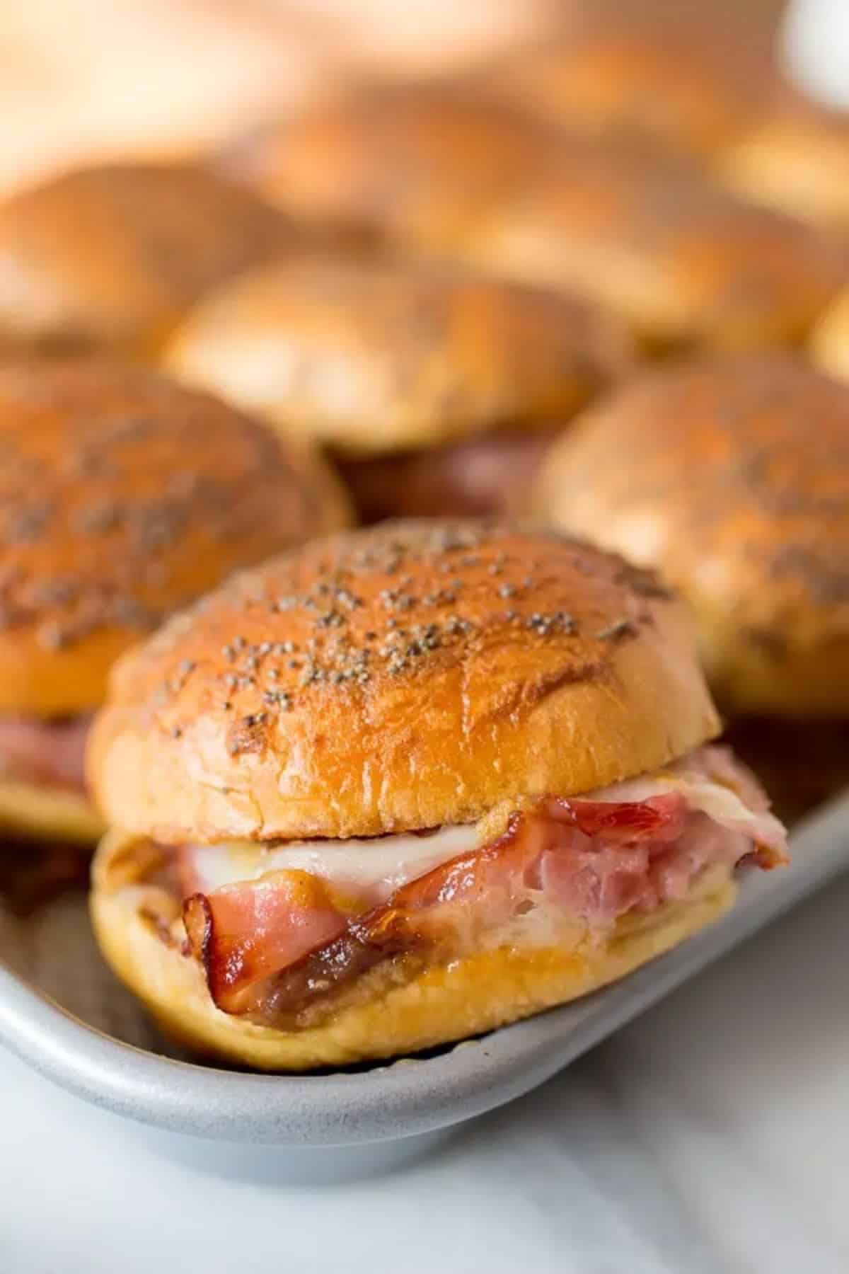 Delicious ham and cheese sandwiches on a baking tray.