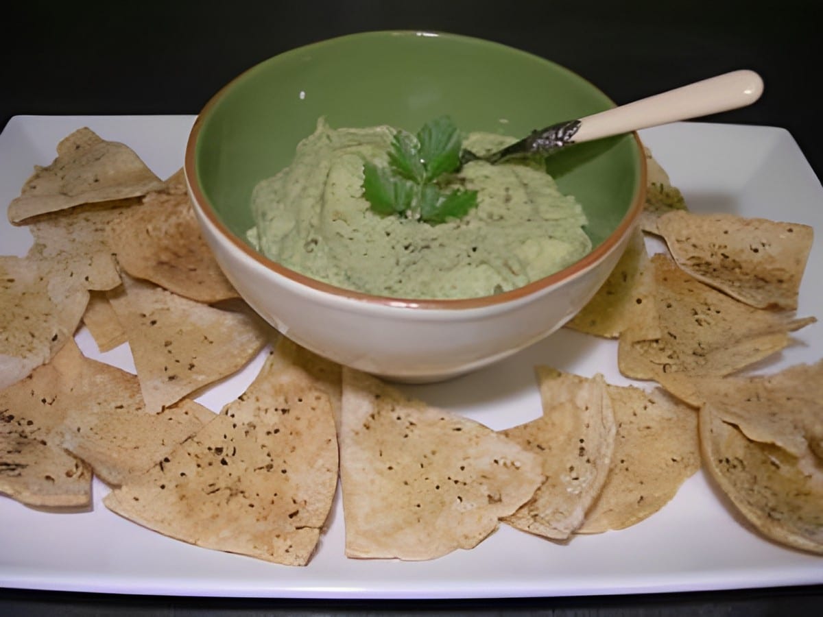 White bean dip with pita chips on a white tray.