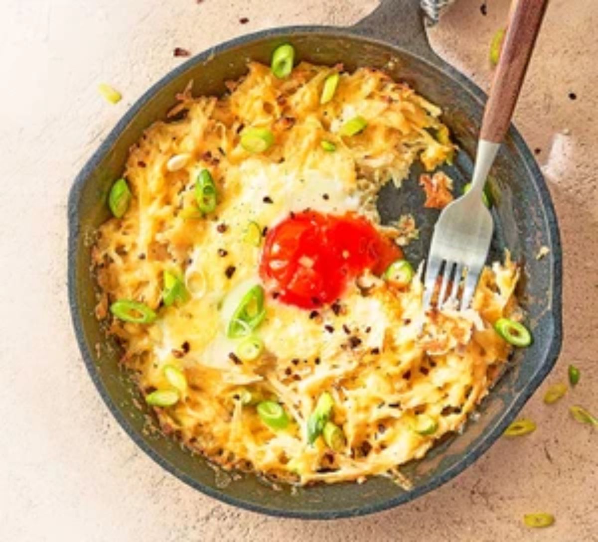 Skillet hash browns and eggs with a fork.
