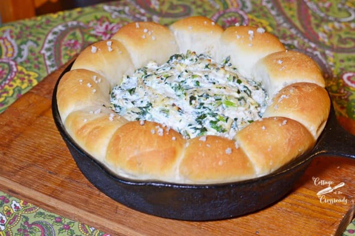 Turnip dip with bread ring in a black skillet on a wooden tray.