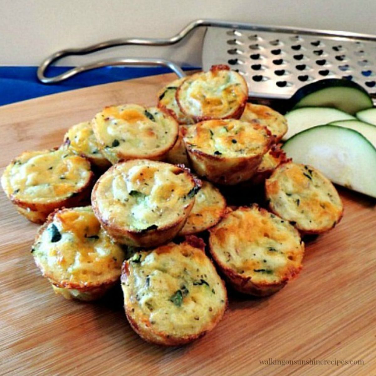A pile of easy zucchini puffs on a wooden cutting board.