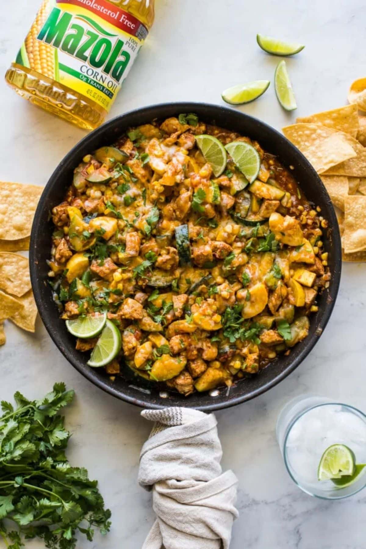 Chicken and summer squash in a black skillet.