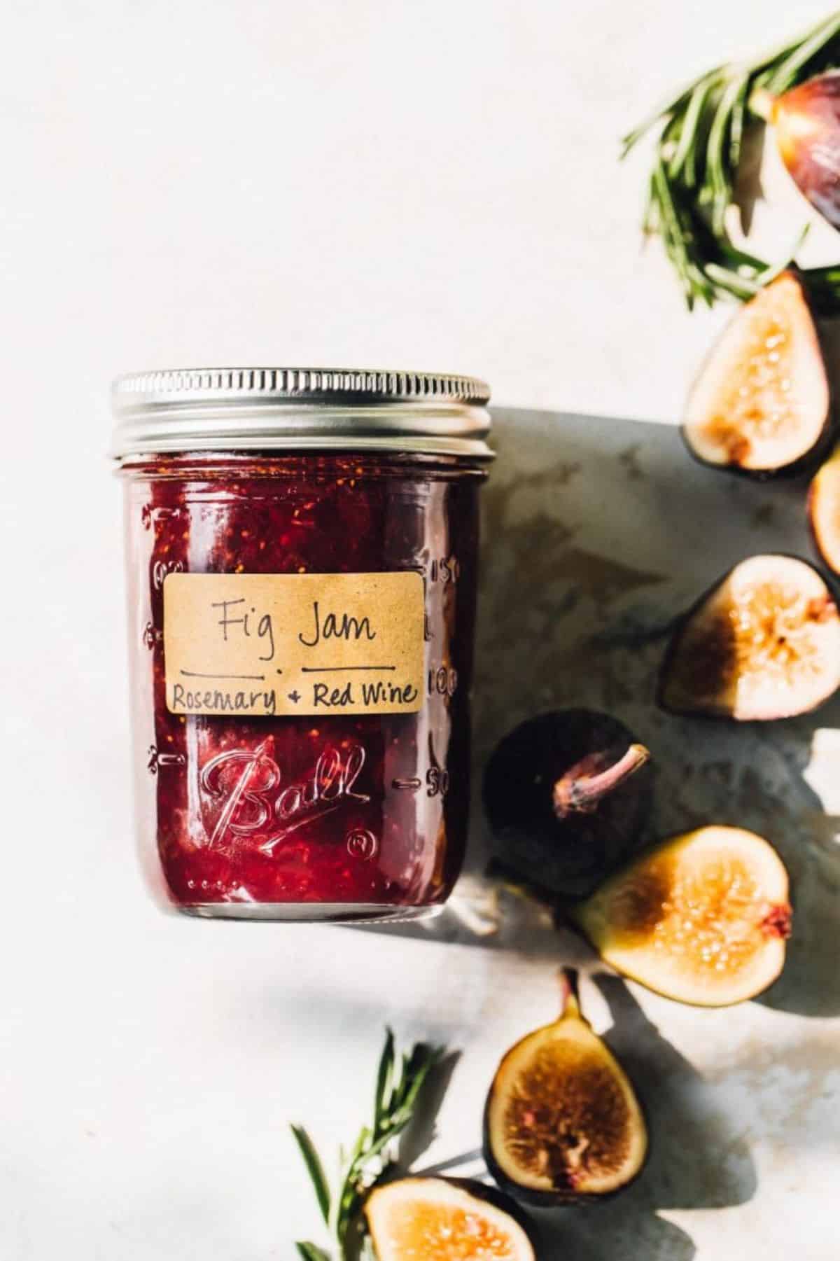 Red fig jam in a glass jar with sliced figs around.