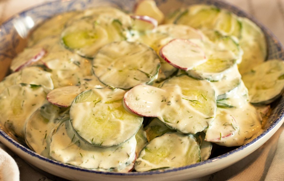 Creamy greek cucumber salad in a blue bowl.