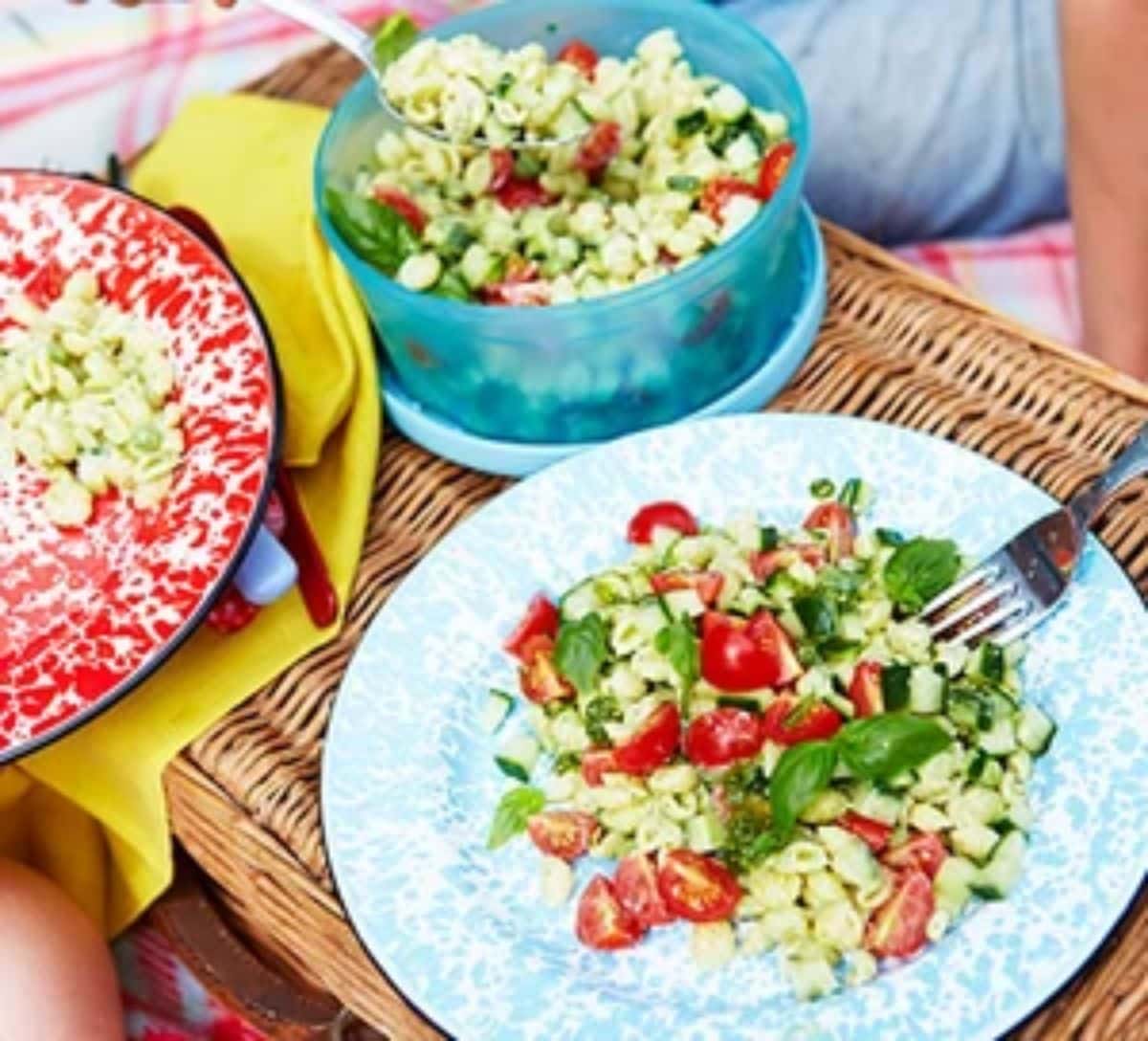 Pesto pasta salad on a blue plate with a fork.