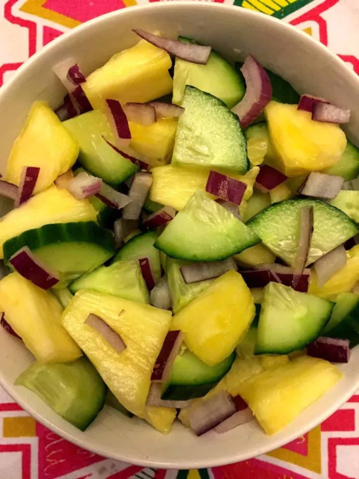 Healthy pineapple cucumber salad in a white bowl.