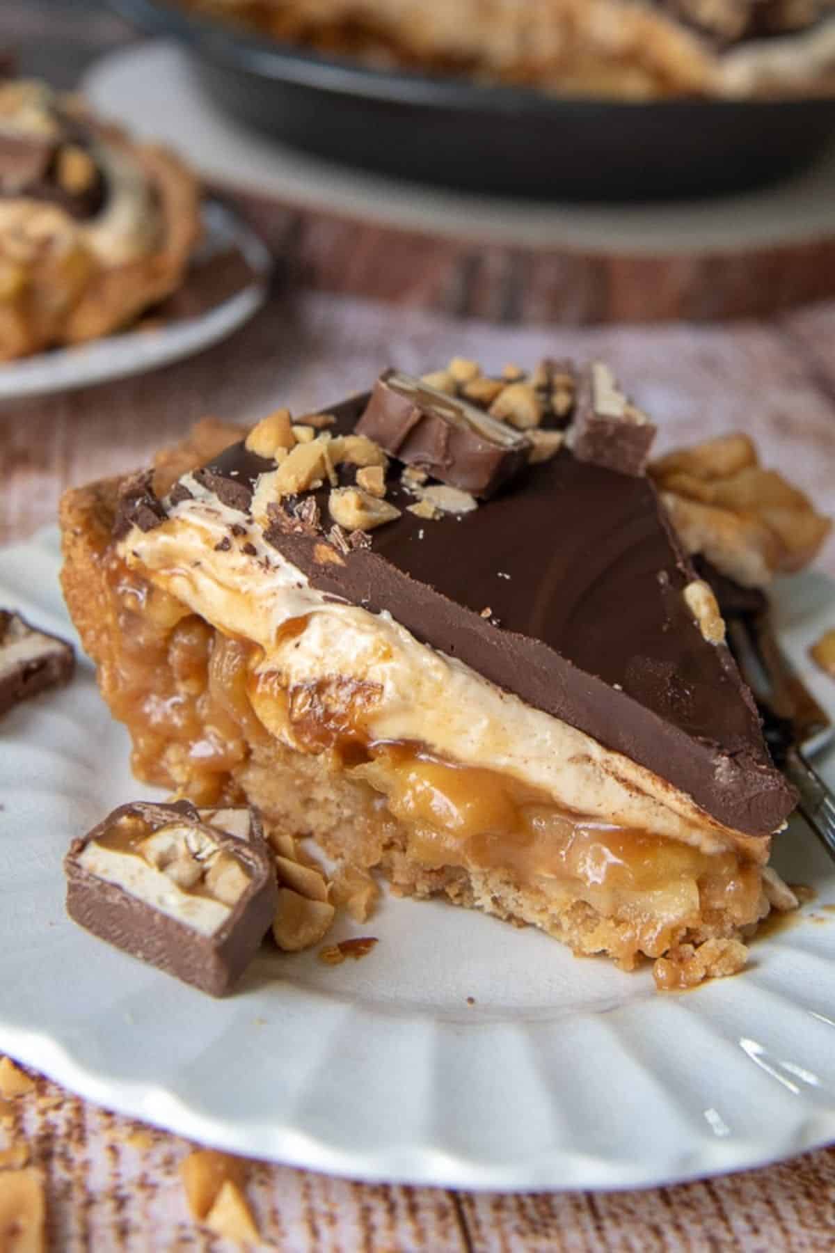 A piece of delicious snickers pie on a white plate.
