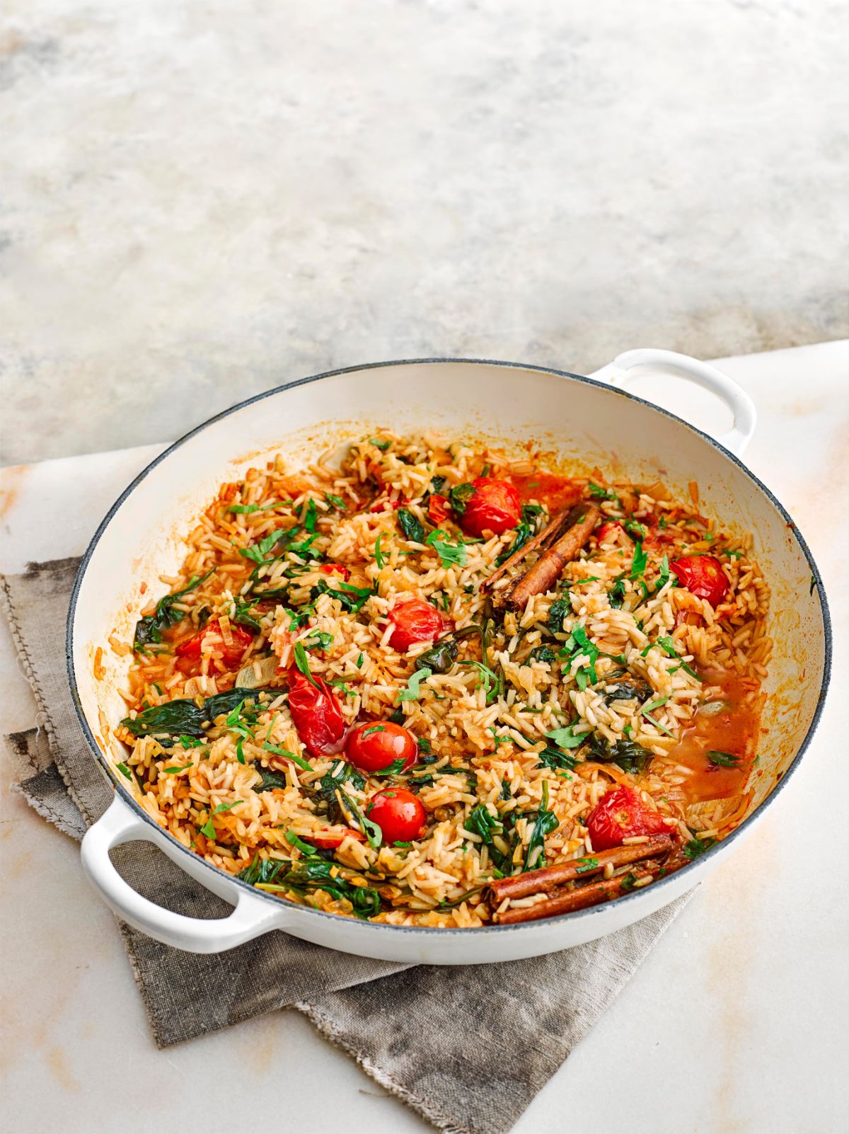 Delicious lemon spinach and cherry tomato pilaf in a white bowl.