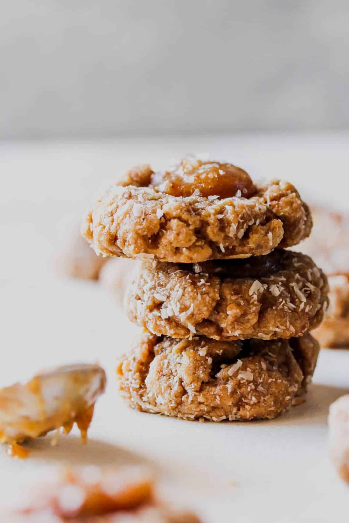 A stack of vegan salted caramel coconut thumbprint cookies.