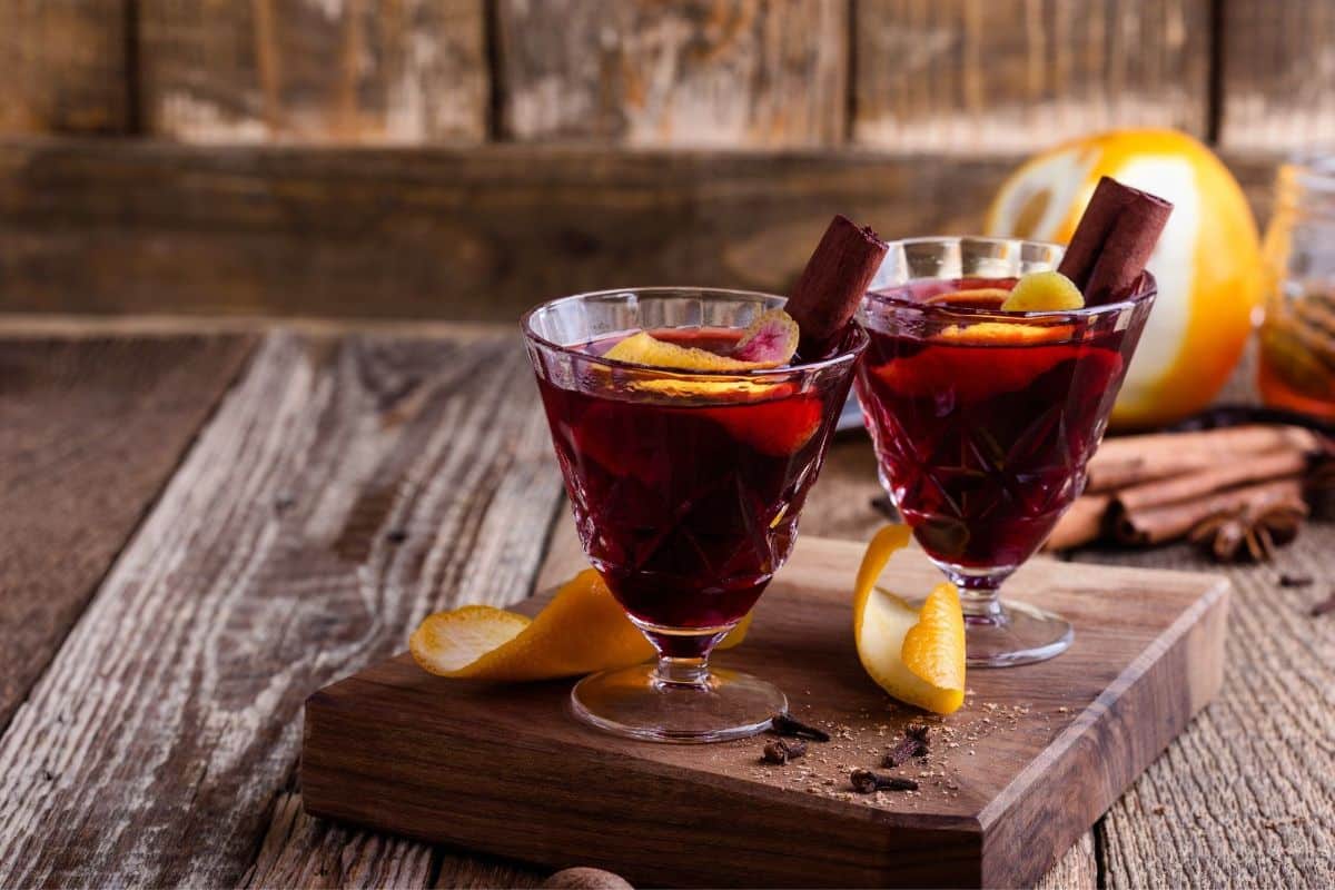 Mulled wine with lemon and cinnamon sticks in tall glasses.