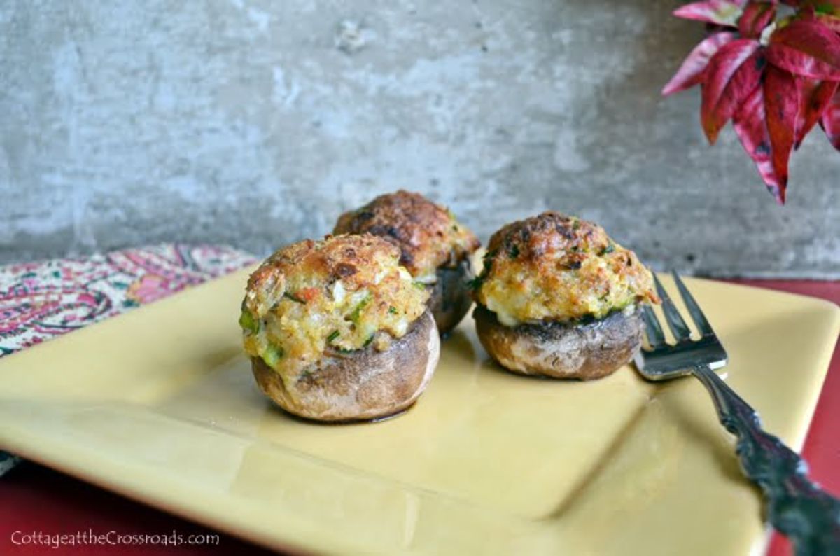 Three lowcountry crab and pimento cheese stuffed mushrooms on a yellow plate.