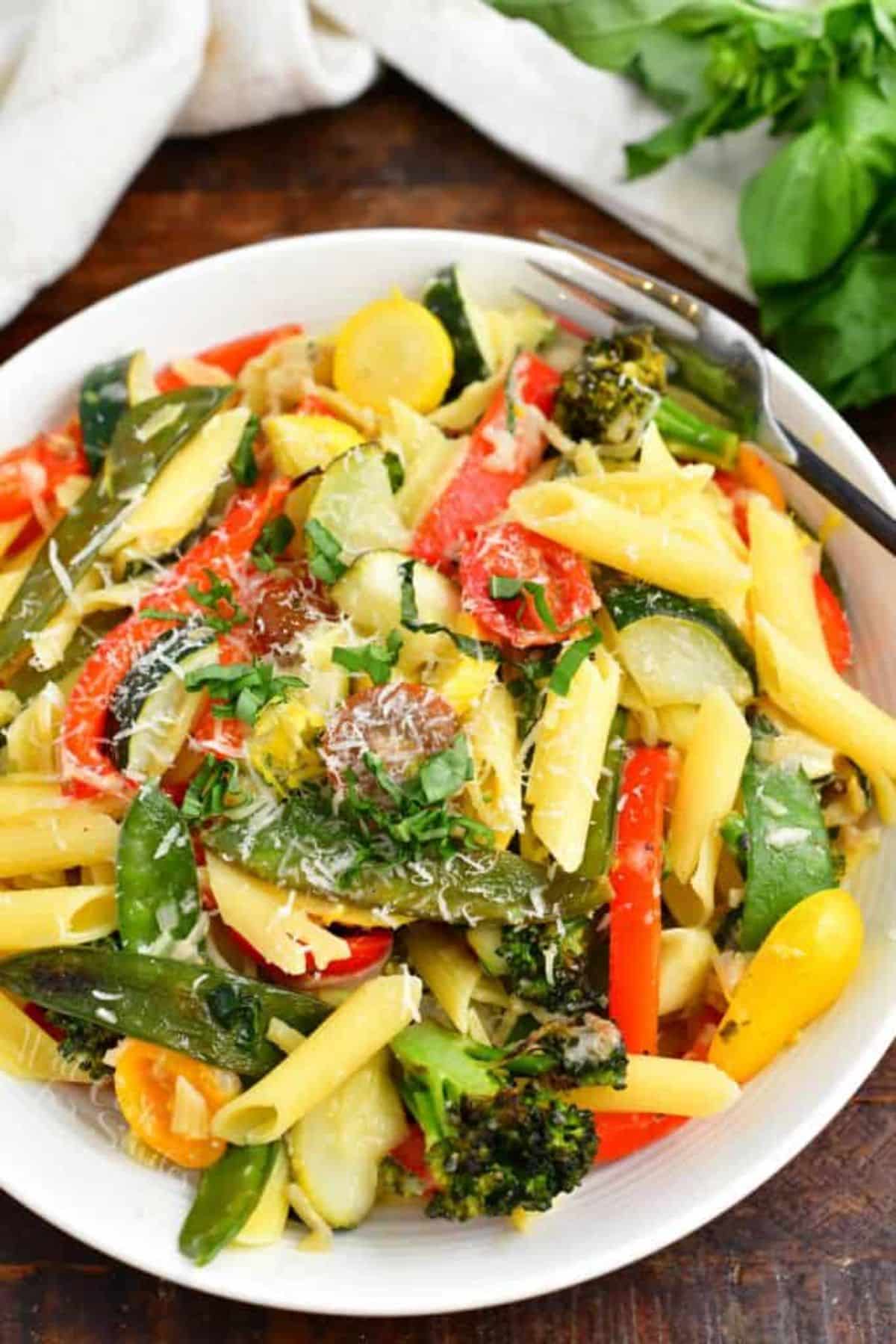 Pasta primavera on a white plate with a fork.