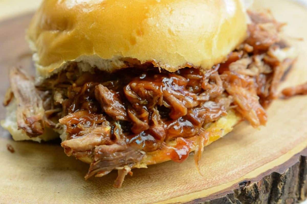 Instant pot dr. Pepper pulled pork burger on a wooden tray.