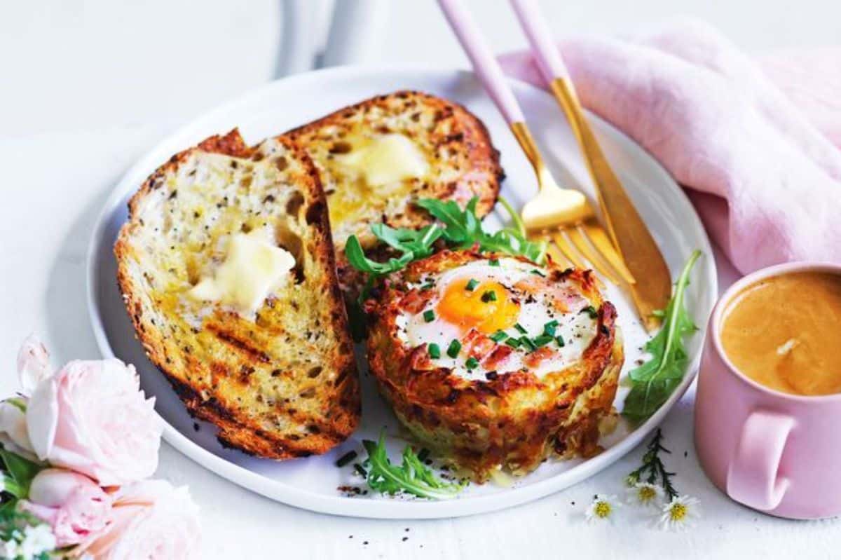 Hash brown egg cups with cutlery on a white tray.