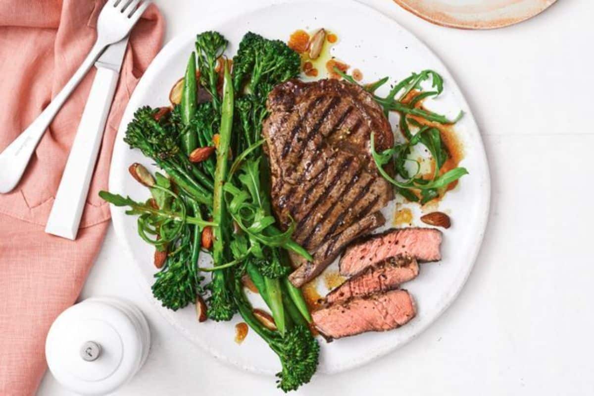 Chargrilled steak with baby broccoli on a white plate.