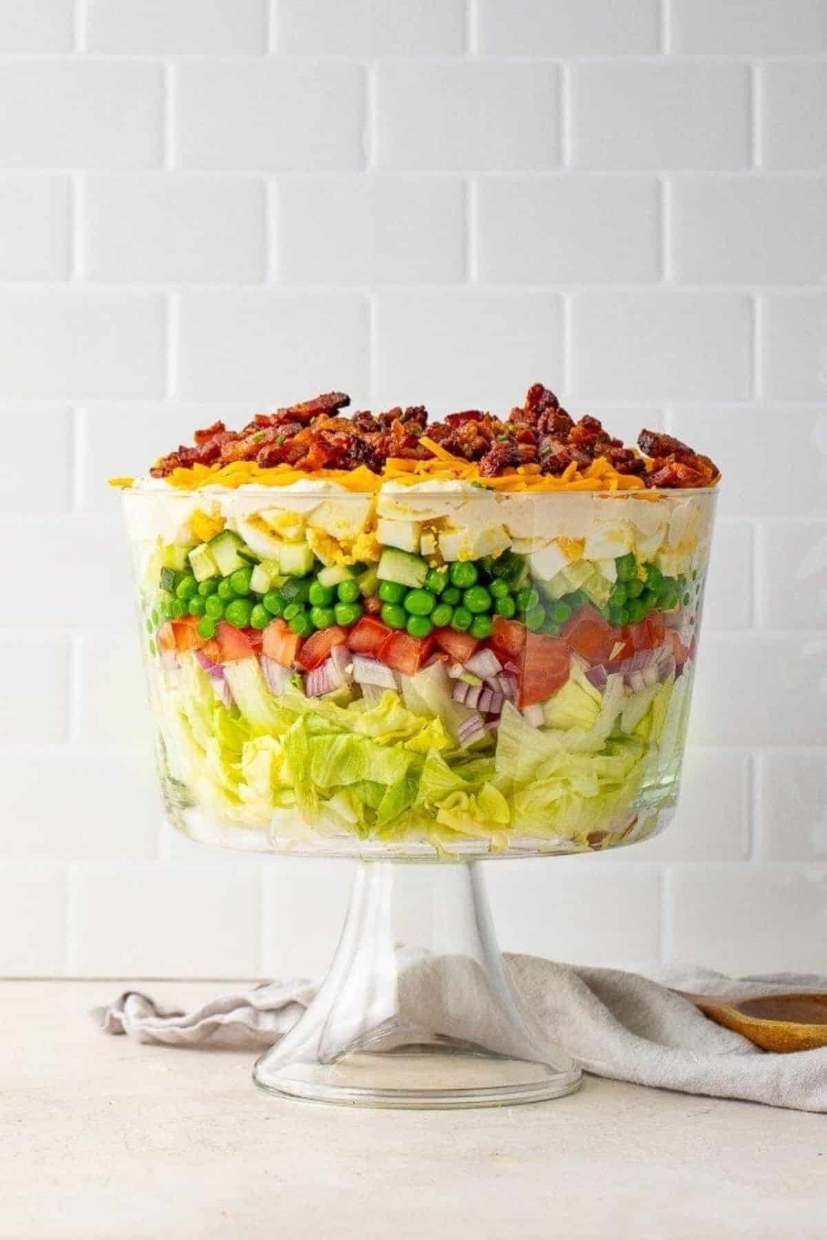 Delicious seven layer salad in a tall glass bowl.