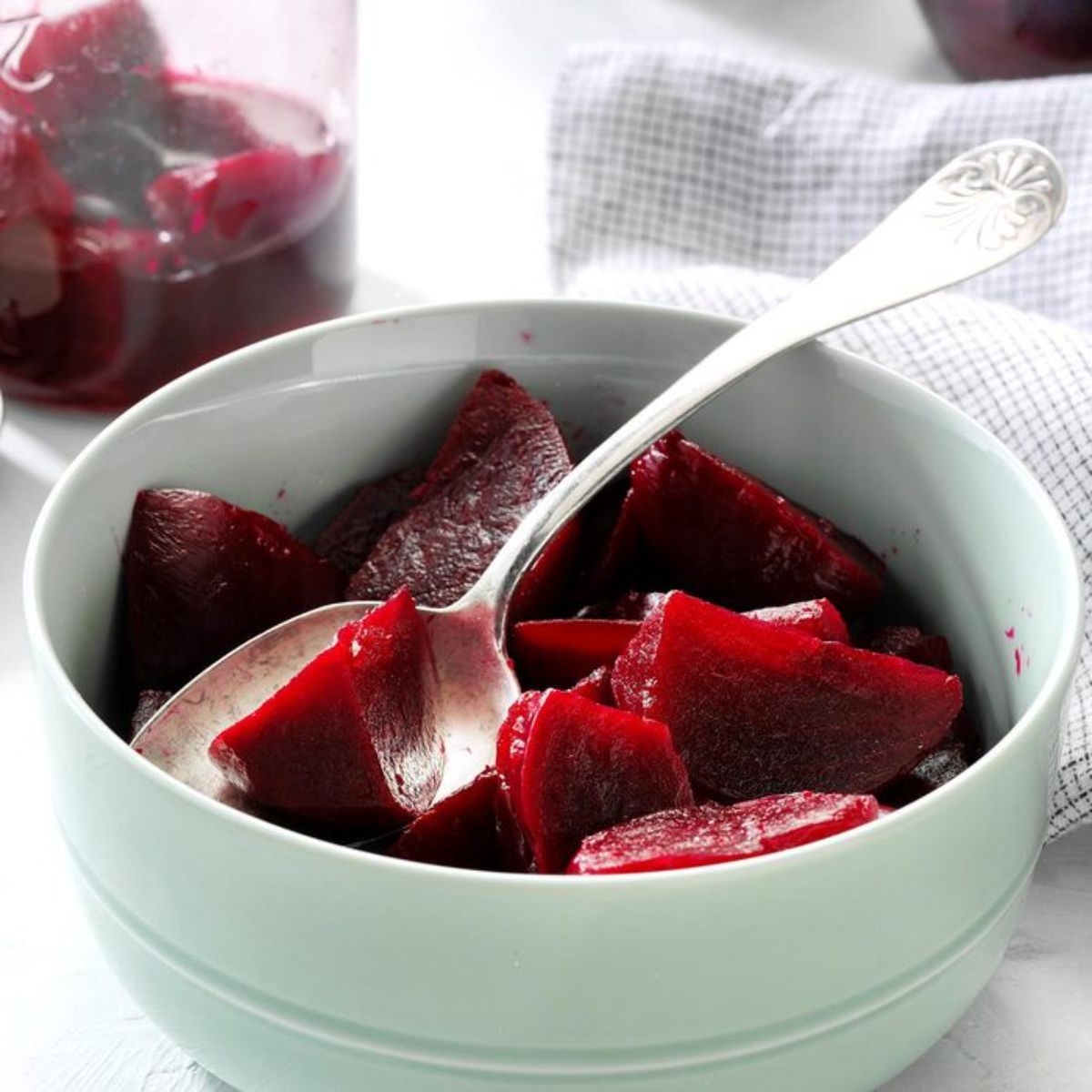 Spicy pickled beets in a white bowl with a spoon.