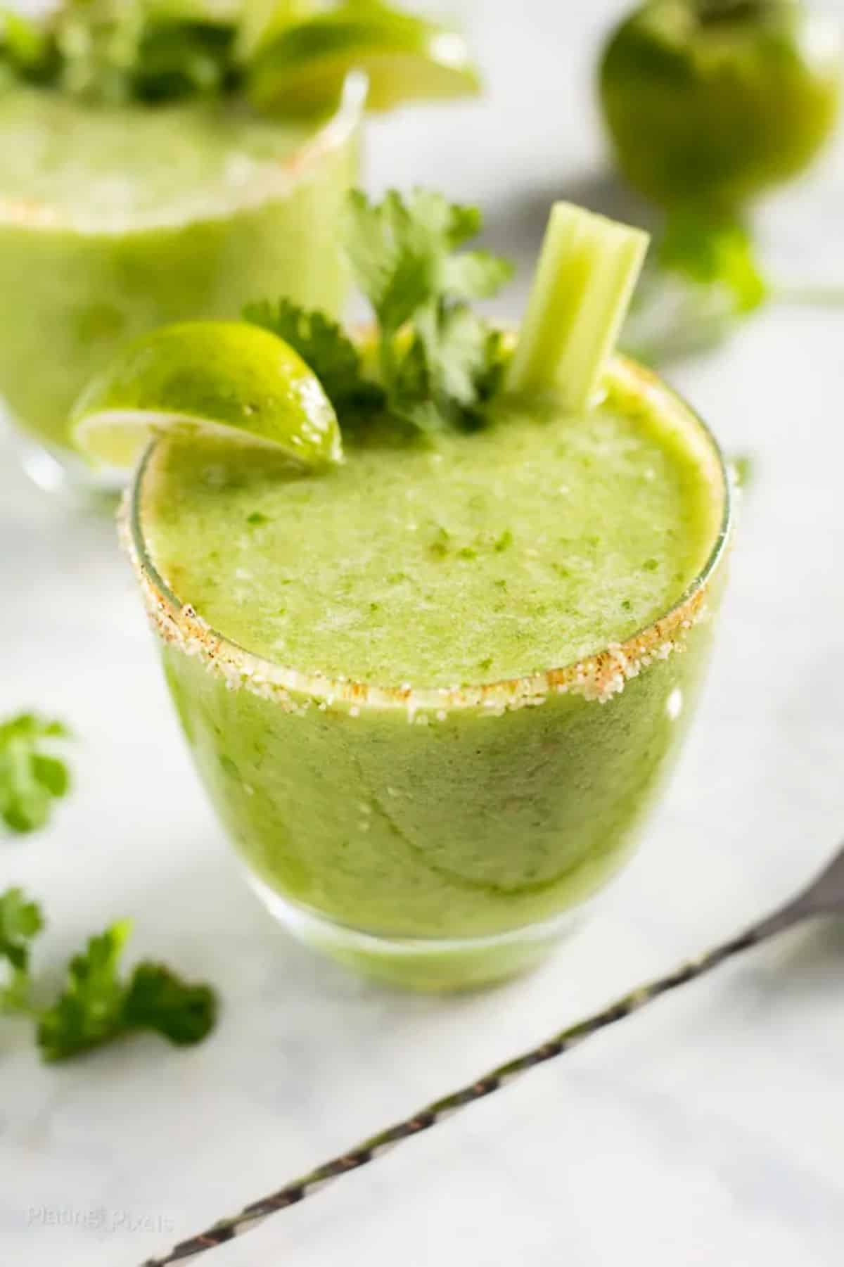 Green bloody mary mix in a glass cup.